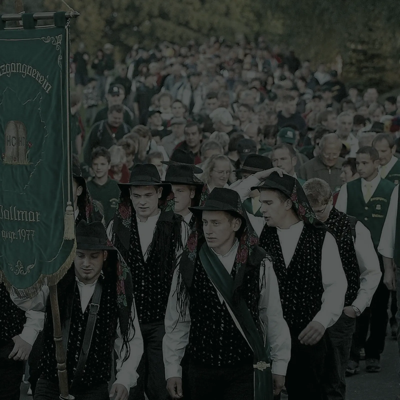 Der Zug durch das Dorf: vorneweg die Fahne, dahinter die Burschen und der ganze Ort